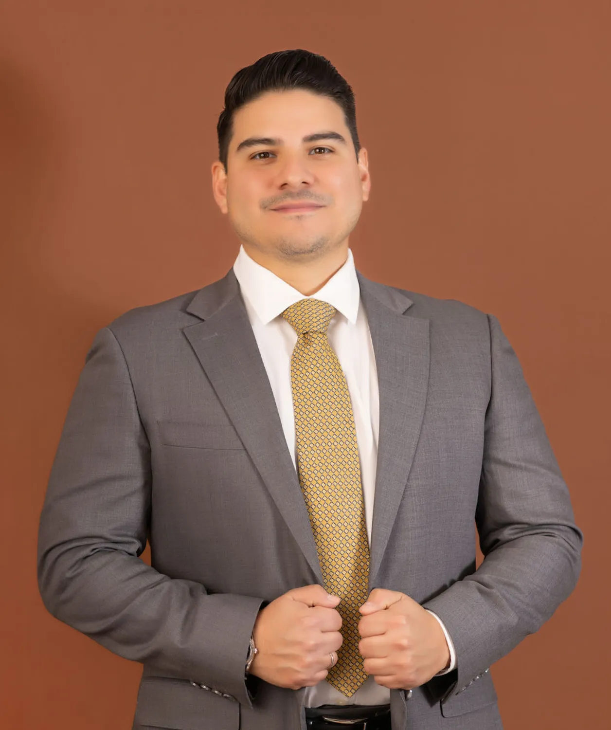 George Orellana standing in a gray suit