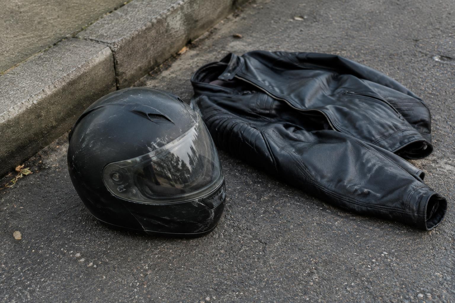Motorcycle helmet and riding gear placed near a roadway after an accident